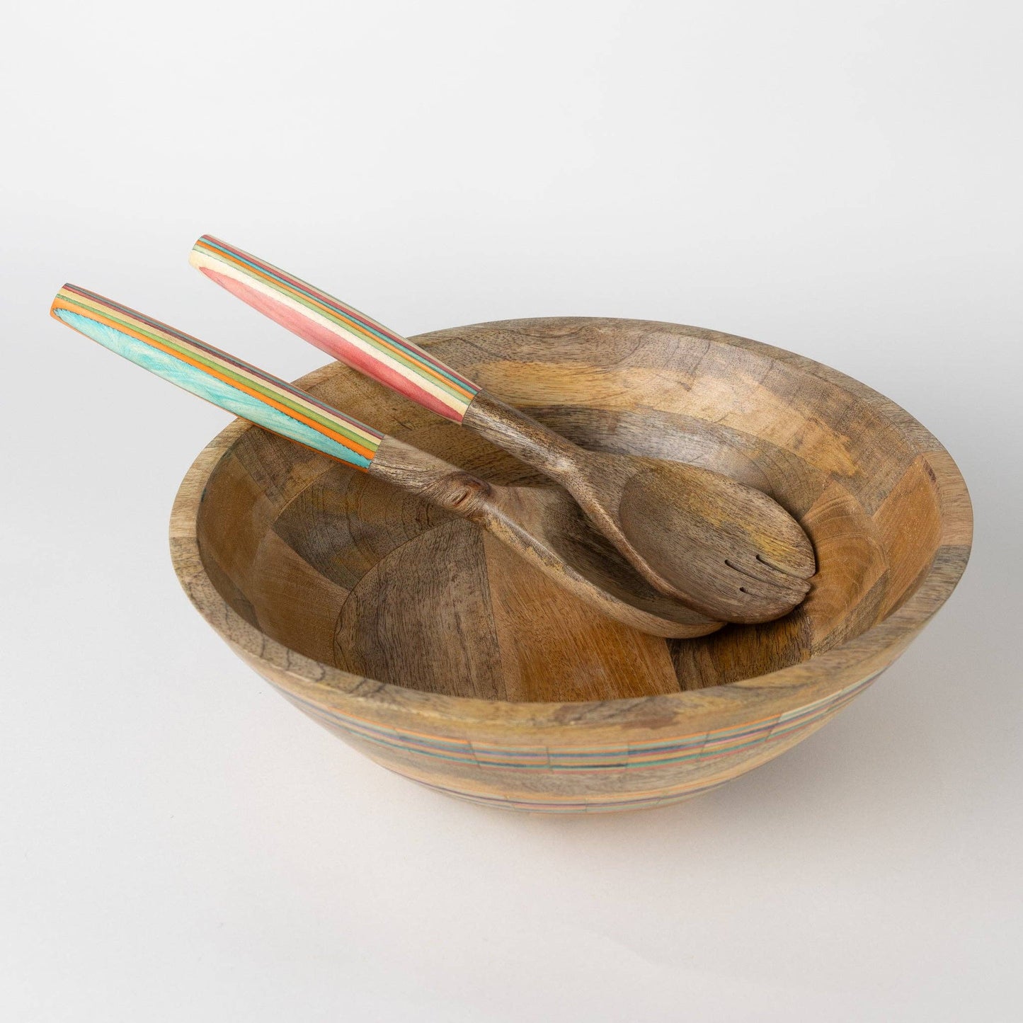 Wooden bowl with two wooden spoons and colorful tongs on a white background