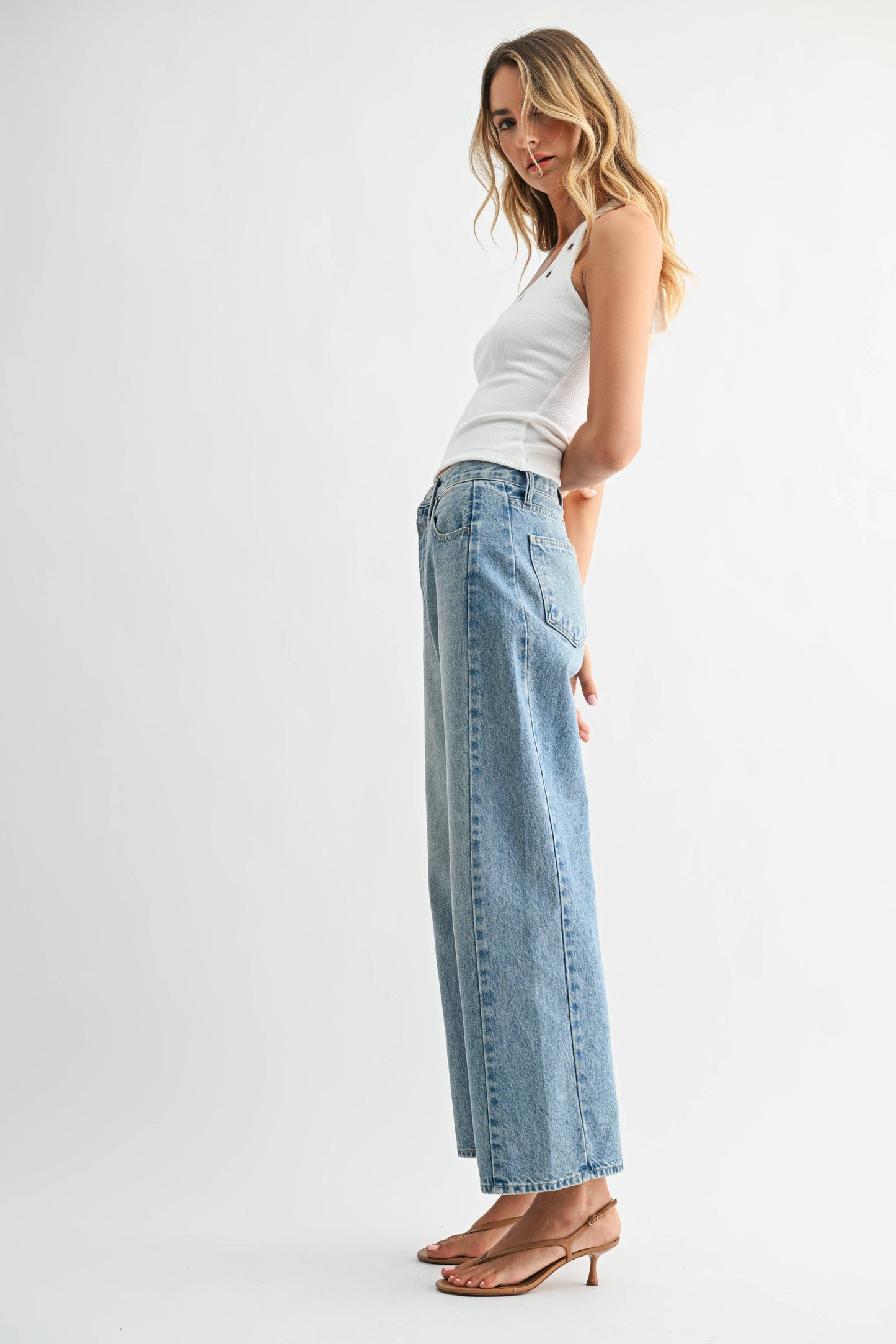 Woman wearing light blue jeans and a white top on a white background