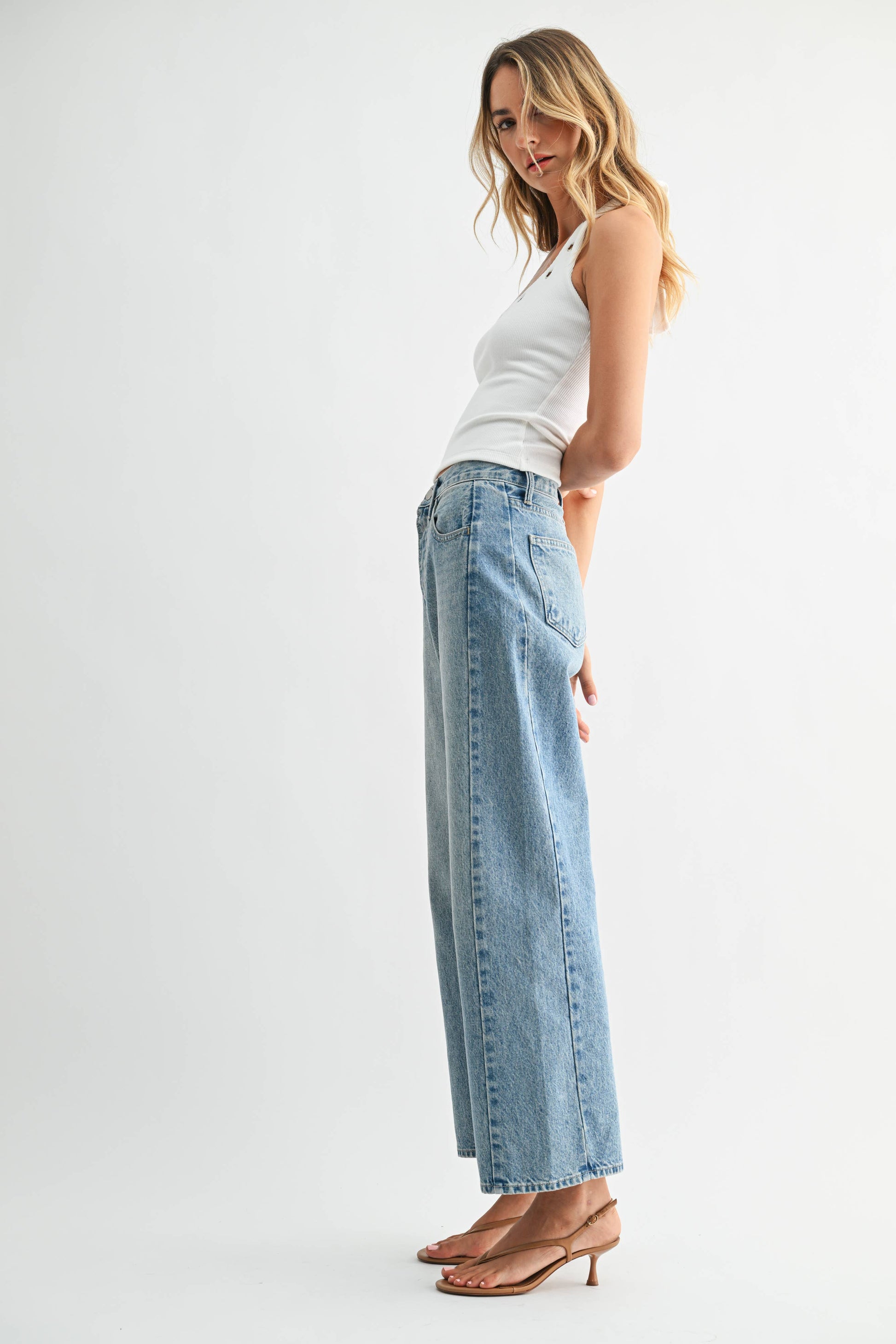 Woman wearing light blue jeans and a white top on a white background