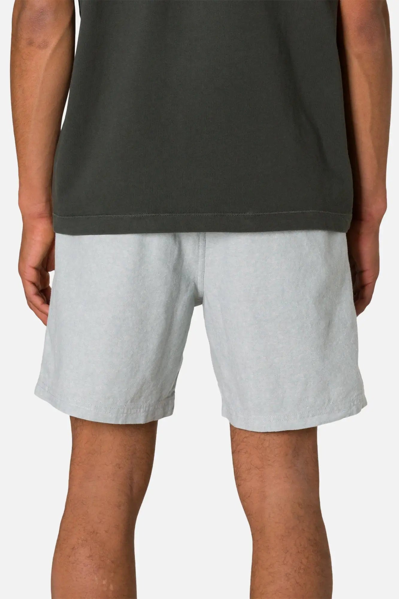 Person wearing gray shorts and a dark sleeveless top on a white background