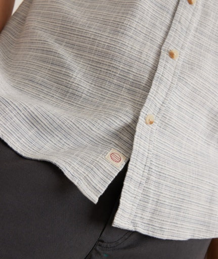 Close-up of a gray button-up shirt with a brand tag on a dark background