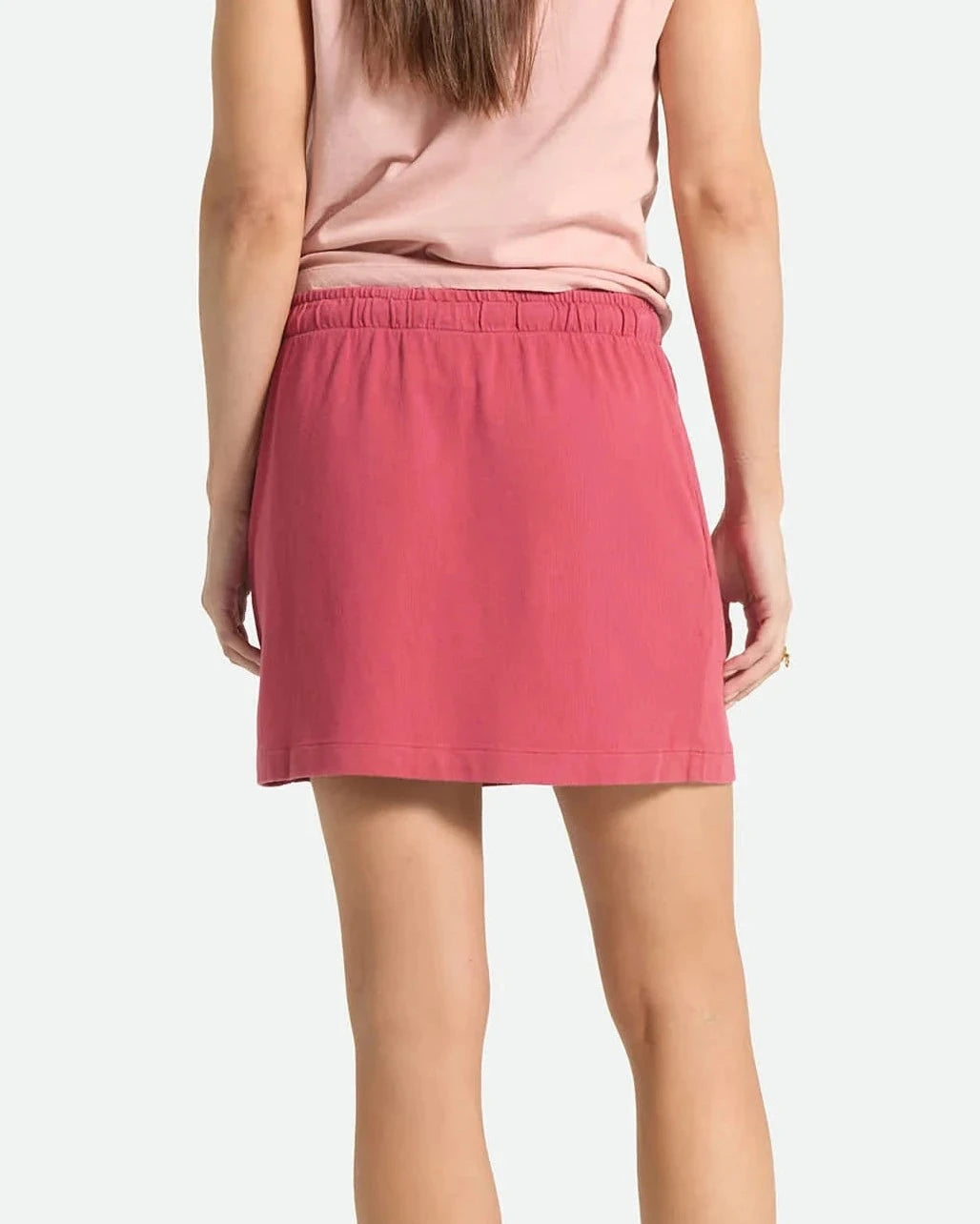 Person wearing a pink skirt and red shoes on a white background
