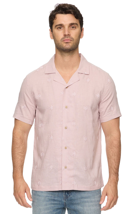Man wearing a light pink short-sleeve shirt with a subtle pattern on a white background