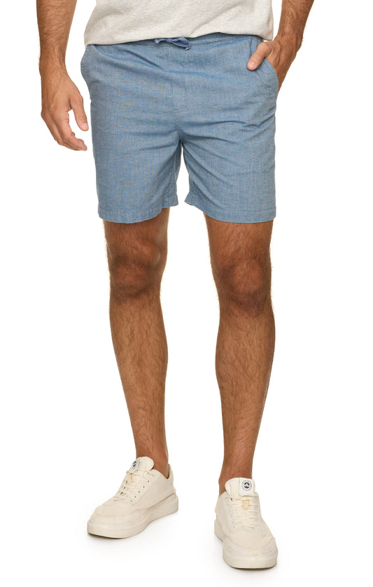 Person wearing light blue shorts and white sneakers on a white background