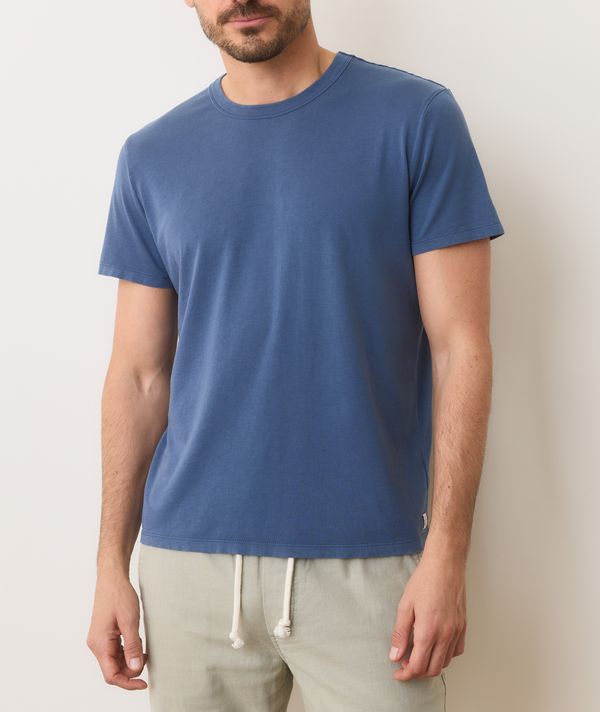 Man wearing a blue t-shirt and light-colored pants against a plain background